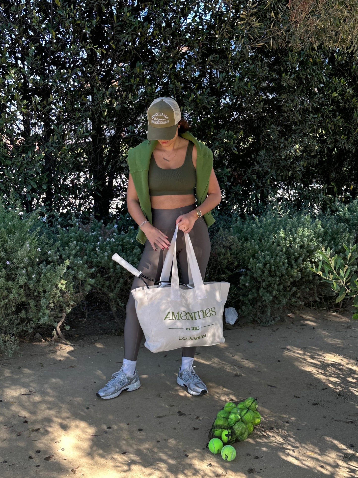 Girl going to play tennis with large canvas tote bag with green Amenities logo embroidered
