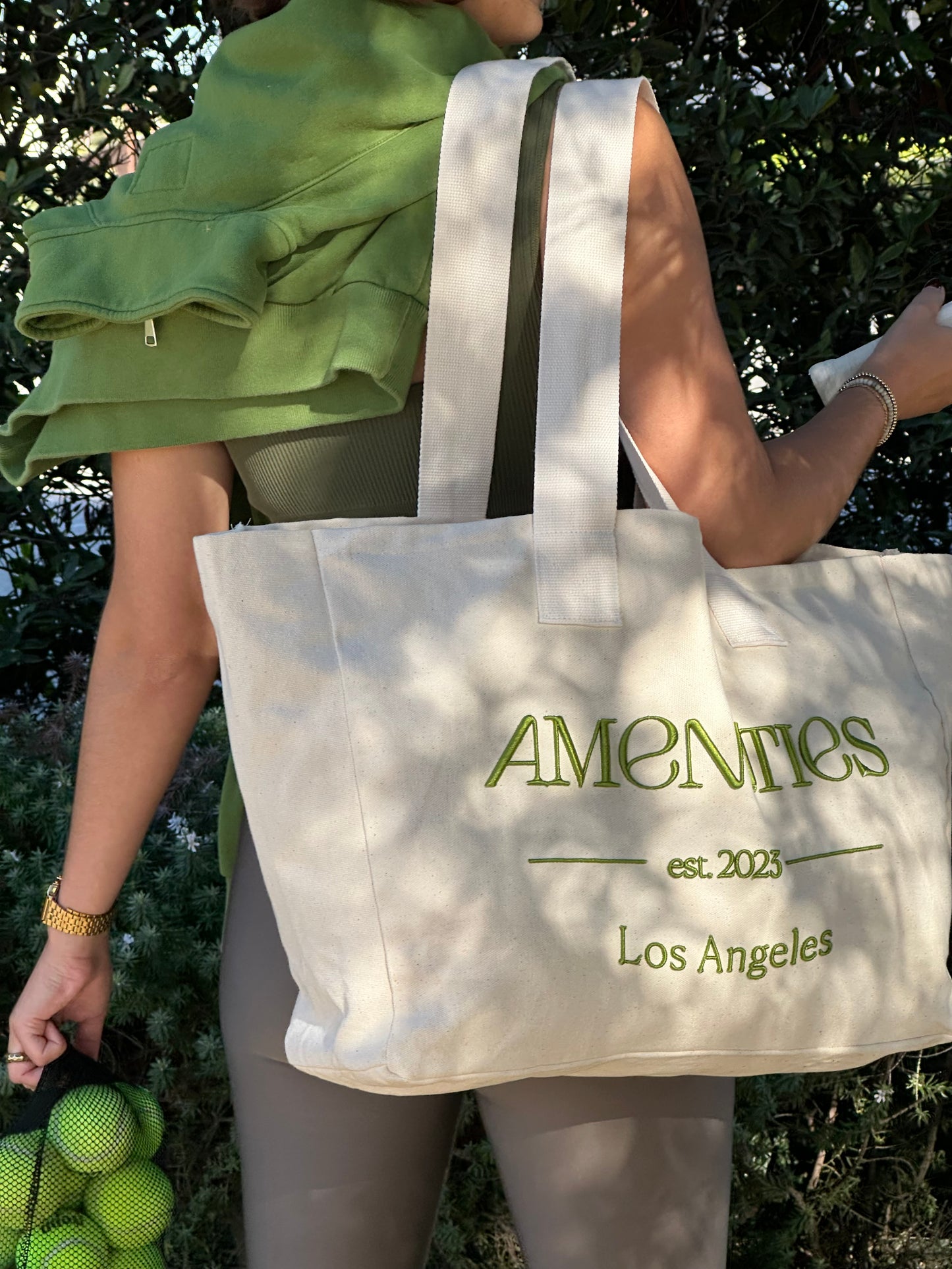 large canvas tote bag with green Amenities logo embroidered