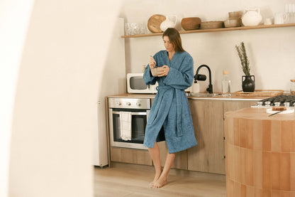 woman in kitchen wearing Sunday Citizen Cascais Bath Robe Deep Sea color