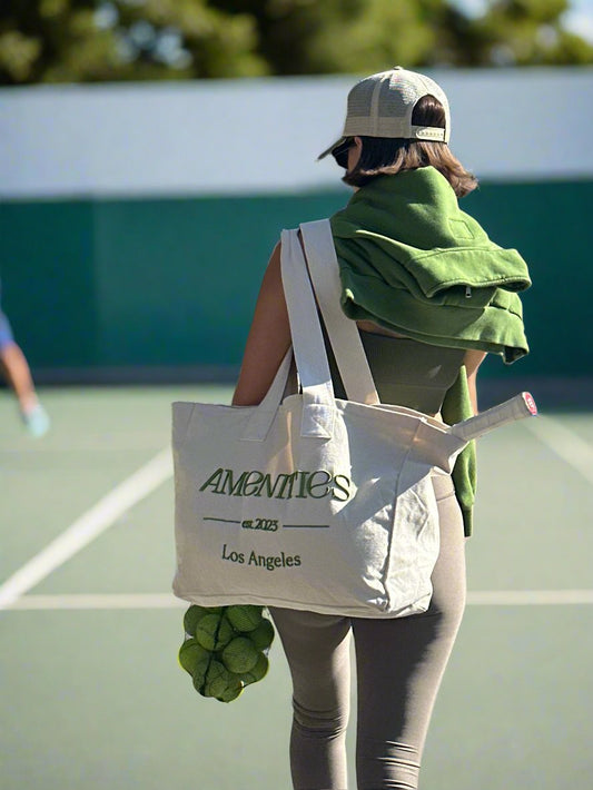 girl walking with large canvas tote bag with green Amenities logo embroidered