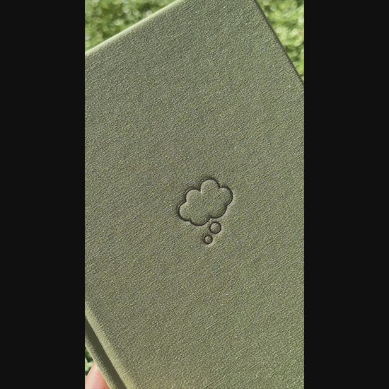 Video of shimmery light green Sprout Green Thought Journal with a champagne gold thought bubble illustration centered on the cover to show off the shine