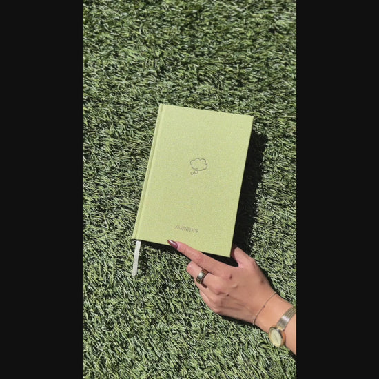 Video of Shimmery light green Sprout Green Thought Journal with a champagne gold thought bubble illustration centered on the cover being opened to reveal lined pages.