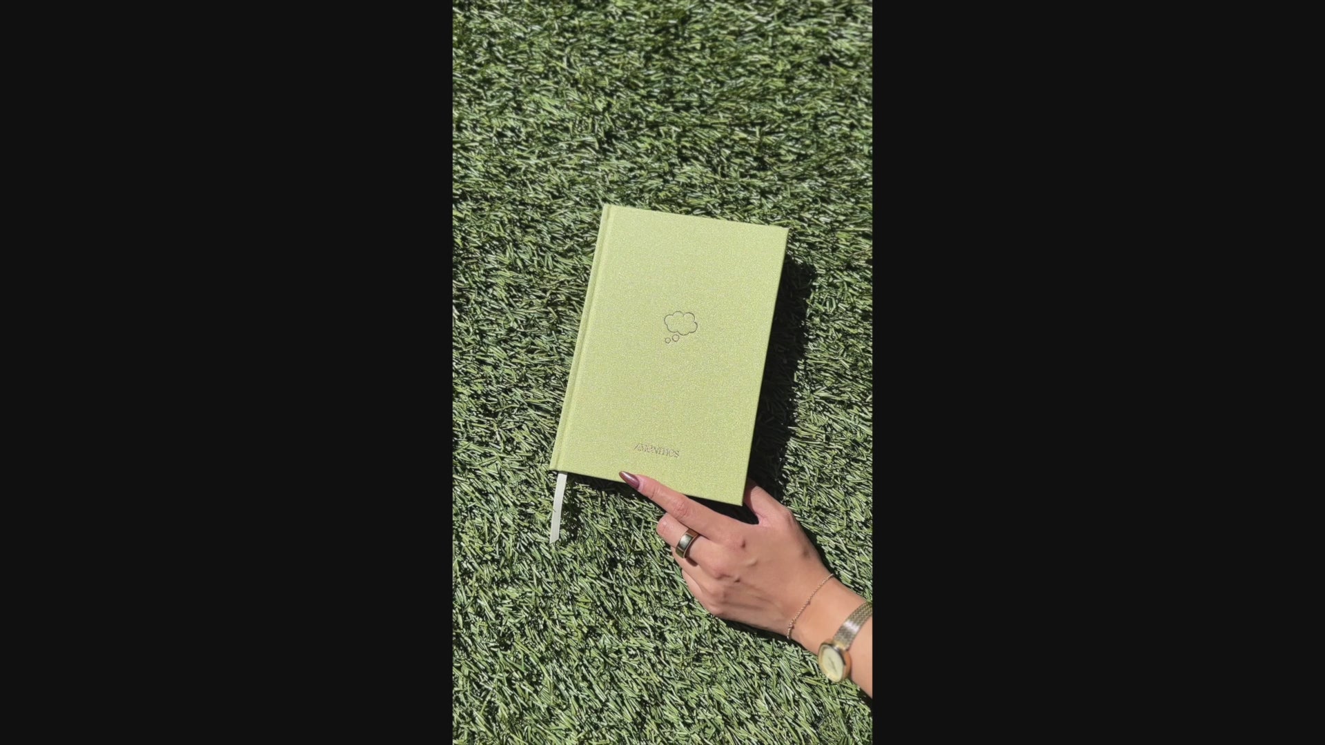 Video of Shimmery light green Sprout Green Thought Journal with a champagne gold thought bubble illustration centered on the cover being opened to reveal lined pages.